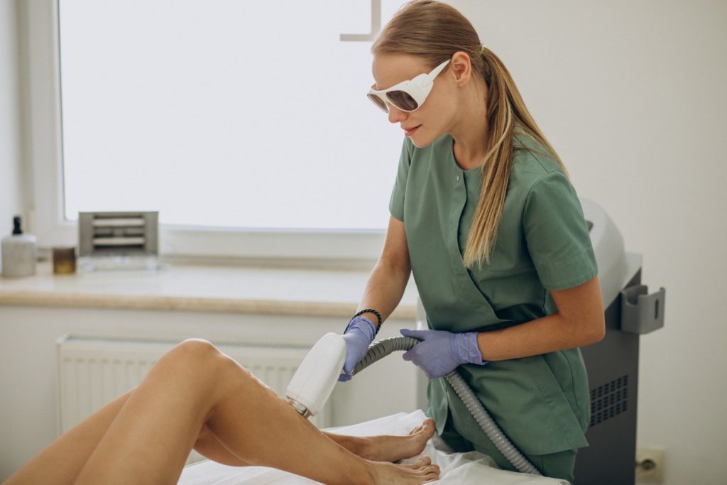 Terapeuta wykonuje zabieg depilacji laserowej nogi pacjentki.